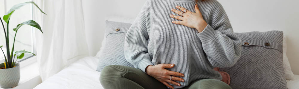 Close-up of torso of young woman with hands on her chest and stomach as she does some focused breathing techniques